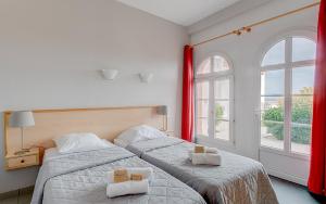 two beds in a room with two windows at Vacancéole - Résidence de L'Océan in La Tranche-sur-Mer +30 photos