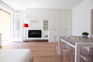a white living room with a table and a television at Fior Apartments Pienzenau in Merano