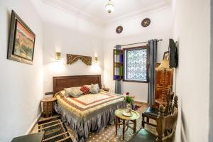 a bedroom with a bed and a table and a window at Riad Jardin Chrifa in Fez
