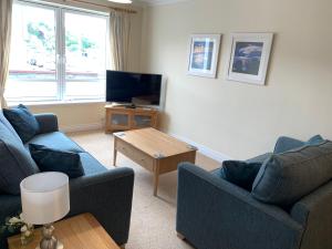 a living room with two couches and a tv at 1/5 Lismore House in Oban