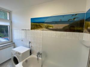 a bathroom with a washing machine and a painting on the wall at Ferienwohnung H&M Immobilien Alsleben 2 in Alsleben