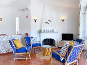a living room with blue chairs and a fireplace at REFÚGIO DO CARANGUEJO - Praia da Luz - WiFi, Private Pool & BBQ in Luz