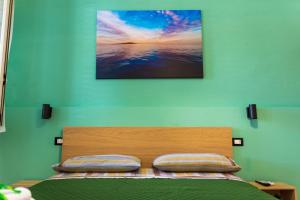 a bedroom with a bed with a picture on the wall at La Casetta sul Mare in Isola delle Femmine