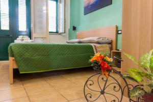 a bedroom with a green bed and a table with flowers at La Casetta sul Mare in Isola delle Femmine