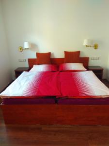 Cama grande con sábanas y almohadas rojas y blancas en Apartmány u Martina, en Javorník