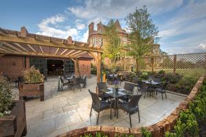 a patio with tables and chairs in front of a building at Horwood House Hotel in Milton Keynes