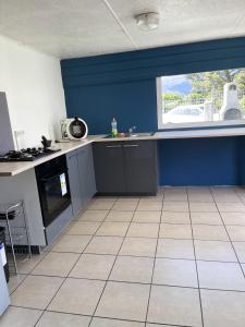 a kitchen with blue walls and a tile floor at Maison de 2 chambres avec terrasse amenagee et wifi a La Plaine des Cafres in La Plaine des Cafres