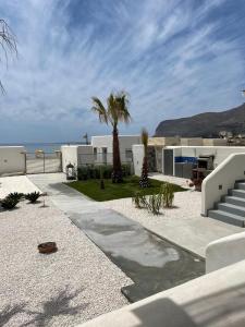 a resort with palm trees and the ocean in the background at Le Casuzze Ammare in Favignana