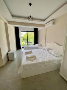 a large white bedroom with two beds and a window at Cilek Butik Hotel in Cesme