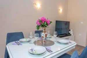 una mesa con platos y un jarrón con flores. en Apartment Vento di Bocche en Kotor