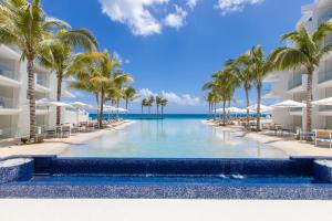 a swimming pool at the resort with palm trees and the ocean at The Morgan Resort Spa & Village in Simpson Bay