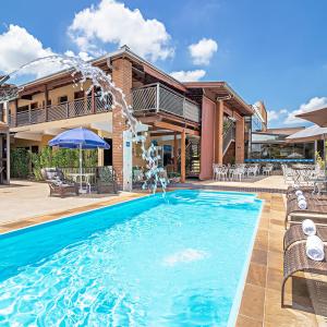 a swimming pool with a fountain in front of a house at Pousada do Lago in Brotas