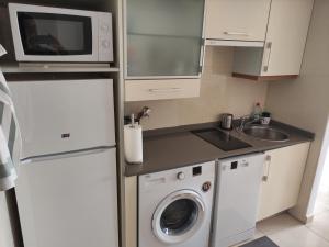 a small kitchen with a washing machine and a microwave at Dumar Puerto Rey in Vera