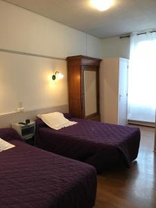 a hotel room with two beds and a window at Hôtel du Clos Fleuri in Lourdes