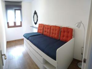 1 dormitorio con 1 cama con almohadas de color naranja en Apartamento Sebreñu 2, en Ribadesella