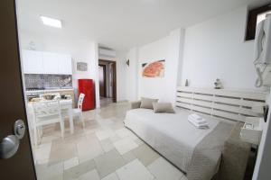 a white room with a bed and a kitchen at PALAZZO ANGIO' in Monopoli