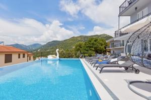 a swimming pool with chairs and a swan on a building at Apartment Kascelan in Kotor