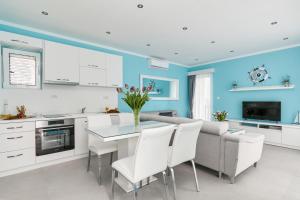 a kitchen with blue walls and a table with white chairs at Apartment Kascelan in Kotor