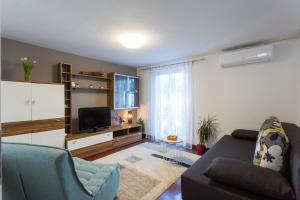 a living room with a couch and a tv at Apartments Lidija - sea view apartment with exclusive right of using hot tub or split level apartment with exclusive right of using pool in Podstrana