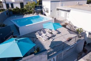 an overhead view of a swimming pool with two blue umbrellas at Apartments Lidija - sea view apartment with exclusive right of using hot tub or split level apartment with exclusive right of using pool in Podstrana