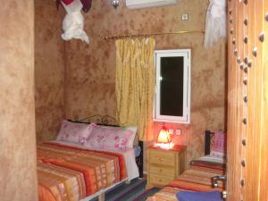 a small bedroom with two beds and a window at Maison d'Hôtes le Ciel Bleu in Tinerhir