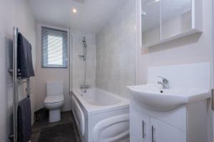 Baño blanco con lavabo y aseo en Brackenborough Hotel en Louth