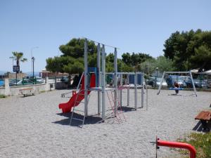 an empty playground with a slide and swings at Gardelis Gardens in Benitses