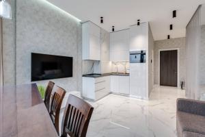 a kitchen with white cabinets and a table and chairs at Luxurious Apartment with panoramic view in the historic center in Kyiv +32 photos