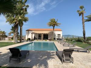 a swimming pool with chairs and a house at Villa Alaya - Luxury Villa with private pool in Partanna