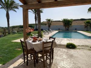 Partanna的住宿－Villa Alaya - Luxury Villa with private pool，一张桌子,上面有白色的桌布,在游泳池边