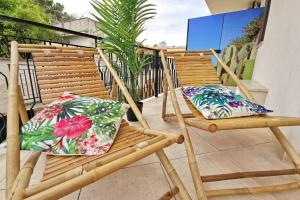 twee bamboe stoelen met bloemenkussens op een balkon bij Loft Palm Beach - 100 metri dalla spiaggia di sabbia bianca e dal mare in Fontane Bianche