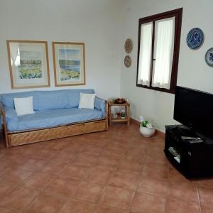 ein Wohnzimmer mit einem blauen Sofa und einem TV in der Unterkunft Casa Maris Best Vacation Ever Villasimius in Villasimius