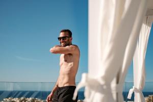 a shirtless man standing on the beach at Hyatt Regency Malta in St. Julianʼs
