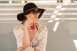 a woman in a hat drinking a drink at Hyatt Regency Malta in St. Julianʼs