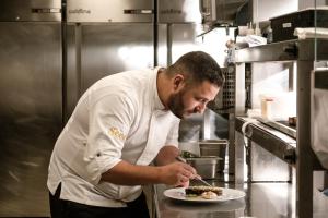 a chef preparing a plate of food in a kitchen at Hyatt Regency Malta in St. Julianʼs