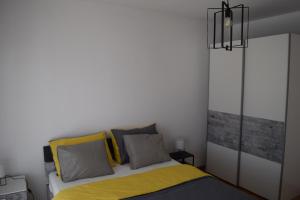 um quarto com uma cama com almofadas amarelas e cinzentas em Dodo em Kaštela