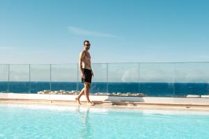 a man walking in a swimming pool at Hyatt Regency Malta in St. Julianʼs