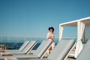 a woman standing on the roof of a building with chairs at Hyatt Regency Malta in St. Julianʼs