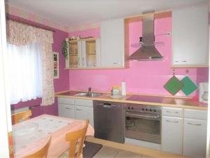 een roze keuken met een tafel en een wastafel bij Ferienwohnung Haus Sonnenschein in Trassem