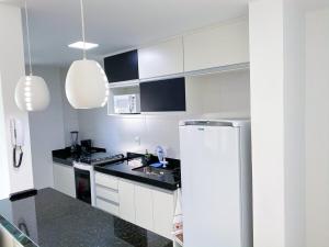uma cozinha com armários brancos e bancadas pretas em Conforto Pertinho das Melhores Praias 101 em Cabo Frio