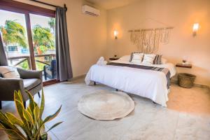 a bedroom with a white bed and a large window at Hotel Macondito Holbox in Holbox Island