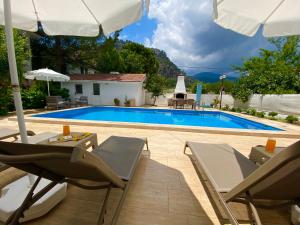 a villa with a swimming pool with chairs and an umbrella at Villa Acar - 4 Bedroom Villa in Dalyan Center, Private Pool&Garden in Mugla