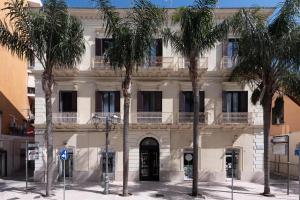 un bâtiment avec des palmiers en face de celui-ci dans l'établissement Maria Vittoria Charming Rooms and Apartments, à Brindisi