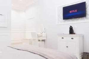 a white bedroom with a bed and a tv on the wall at Charme & Chic Luxury in Rome