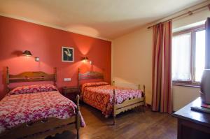 two beds in a room with red walls at Hostal Ayestaran I in Lekunberri