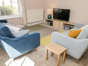a living room with two blue chairs and a tv at Laurel House in Whitby