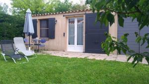 una casa con una puerta azul, dos sillas y una sombrilla en L'ilot de Carpentras en Carpentras