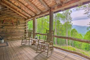 a porch of a log cabin with two chairs and a table at Secluded Cabin with Porch on 39 Acres Ski and Hike in Swiss