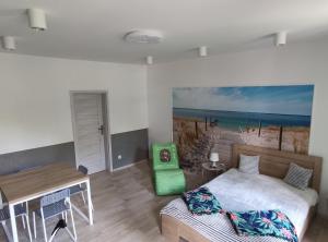 sypialnia z łóżkiem i biurkiem oraz obraz plaży w obiekcie Apartamenty Bulwar Nadmorski, Ustka w Ustce