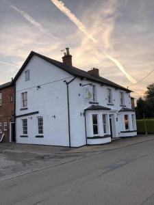 um edifício branco ao lado de uma rua em The Fox and Hounds em Whittlebury